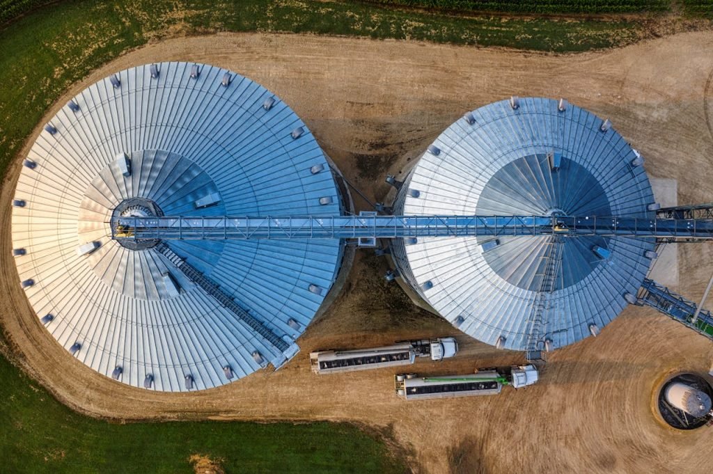 Drone view of two large industrial silos with transportation trucks in Minnesota.